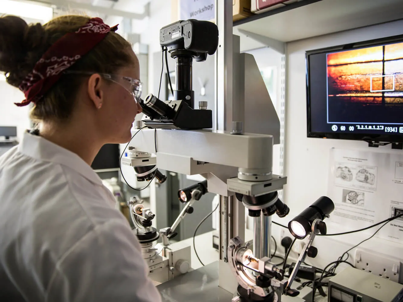 student looking through a large microscope