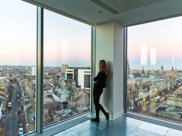 woman in a high building looking out of a window to the Aberdeen skyline