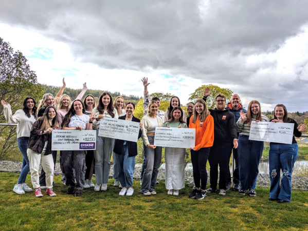 Events students pose with large cheques outside RGU
