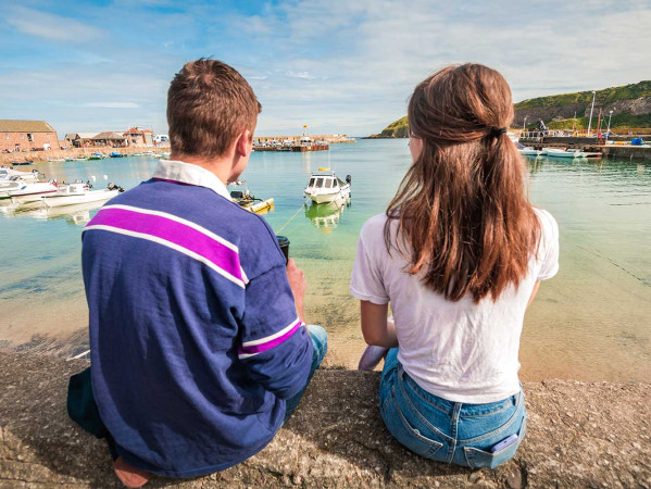 Two people sat at Stonehaven harbour looking at water and boats