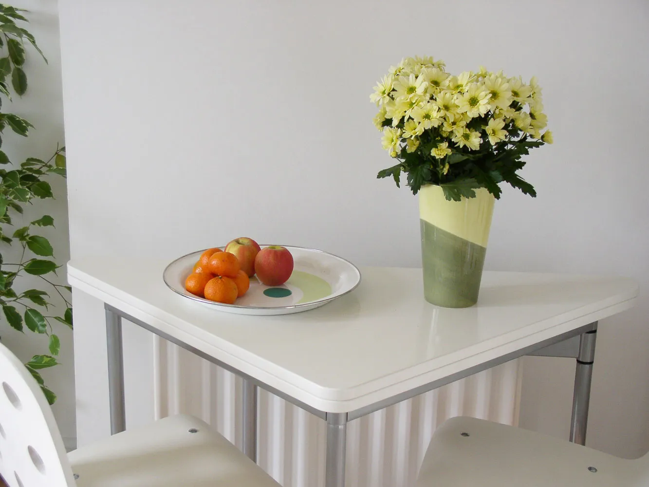 bowl of fruit sitting next to flower vase