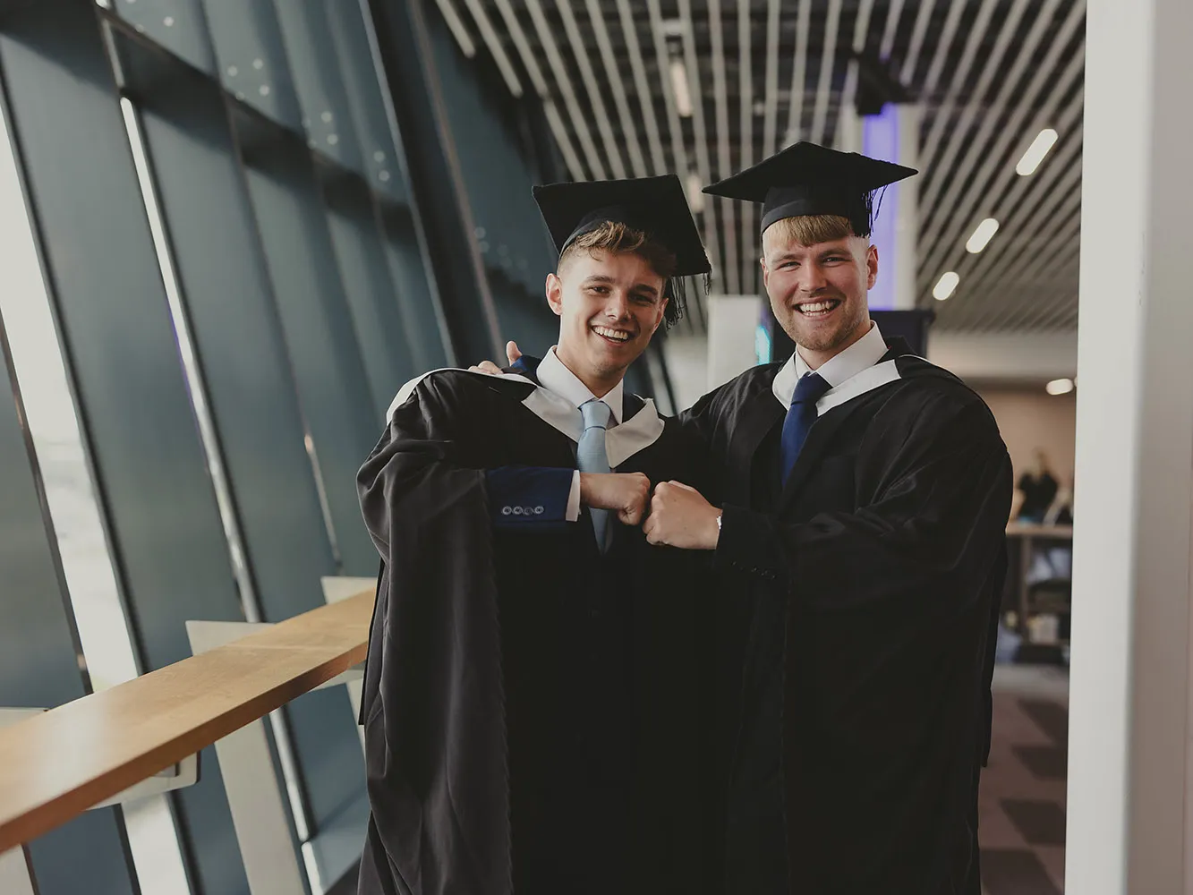 two graduates fist bump