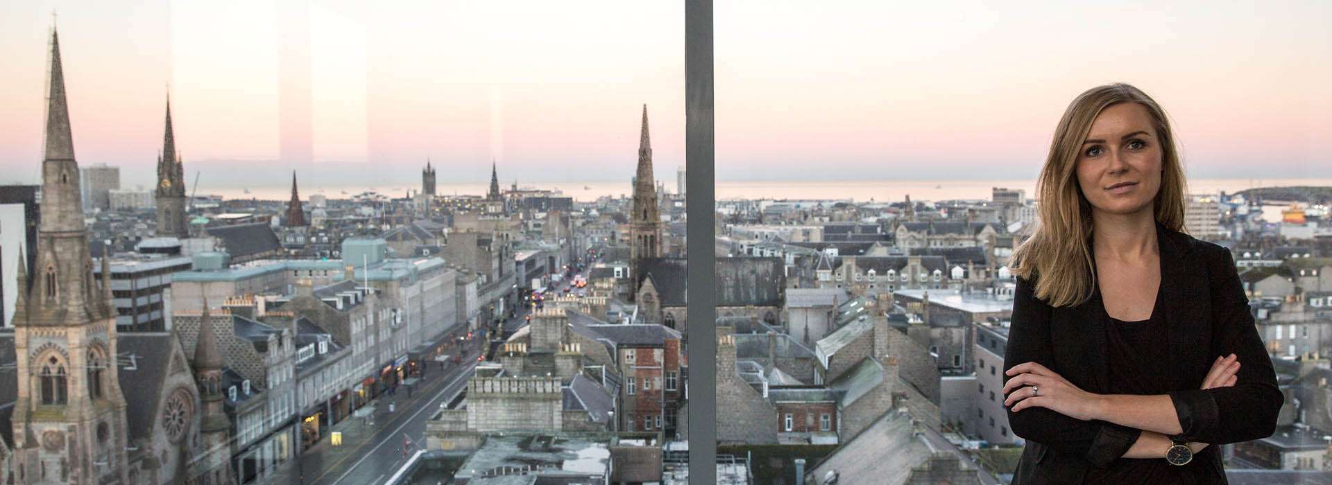 woman next to a window with a view over Aberdeen
