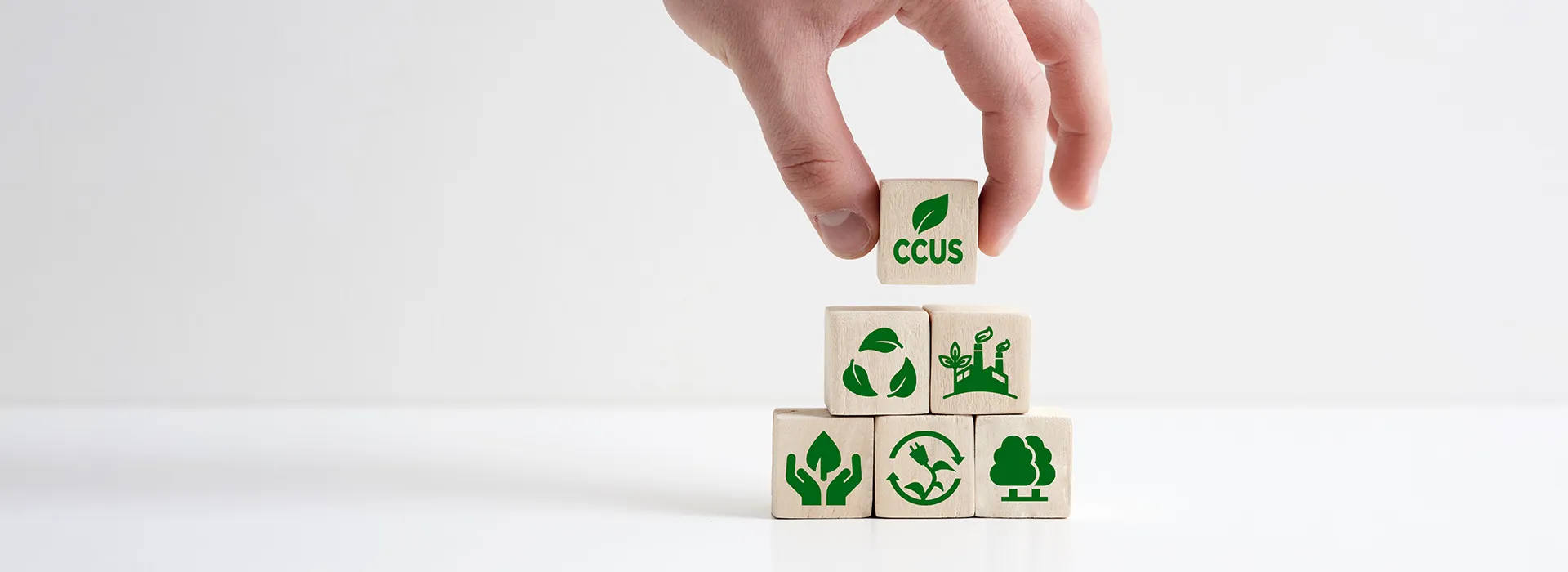 a hand holding building blocks with sustainability icons