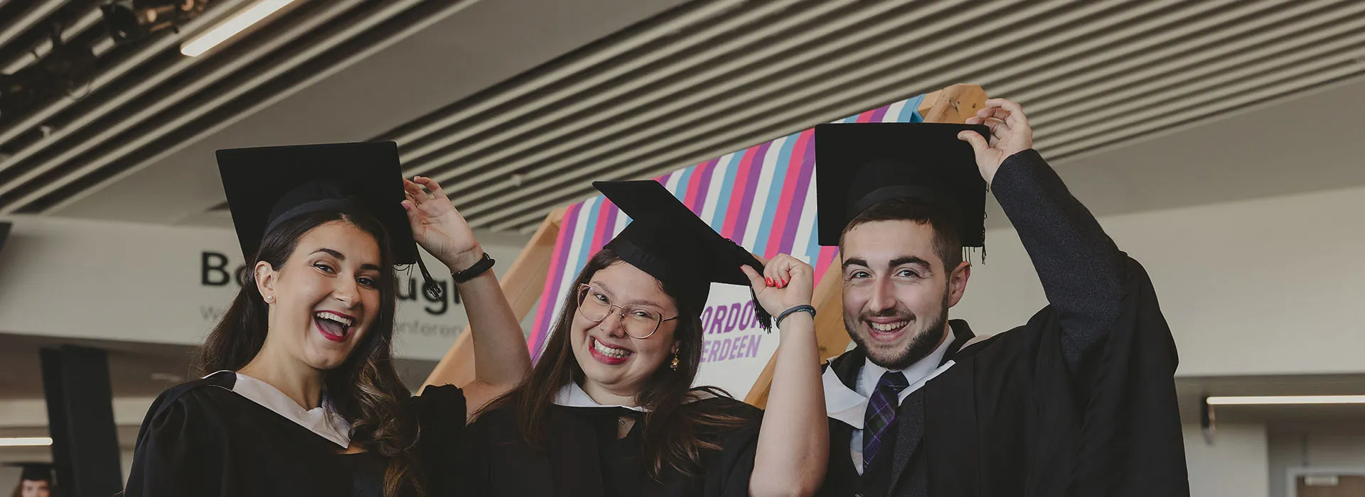 three smiling students graduating