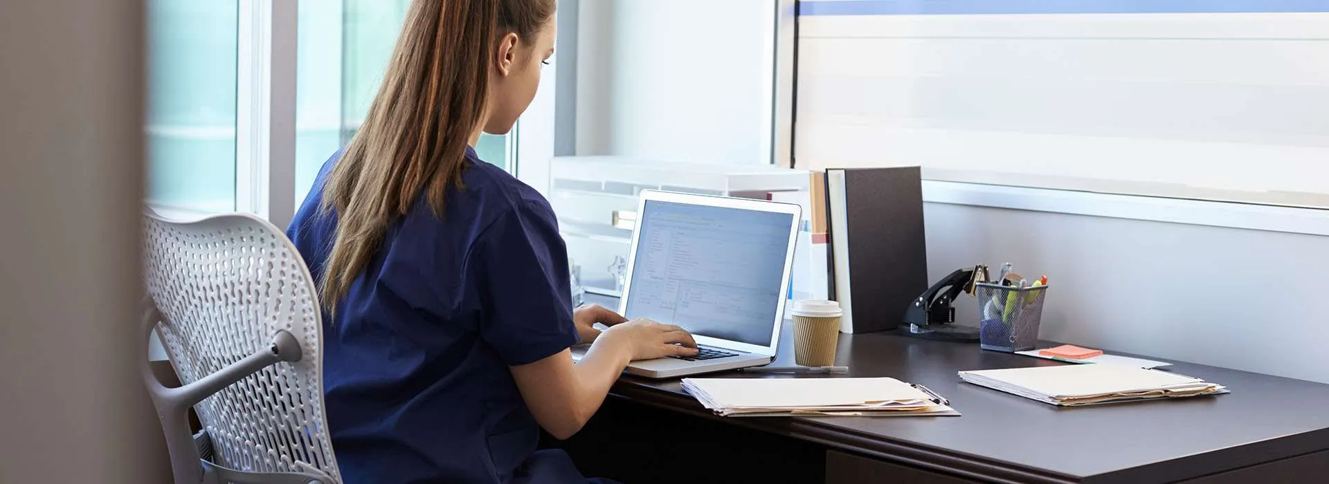Person in scrubs at a computer