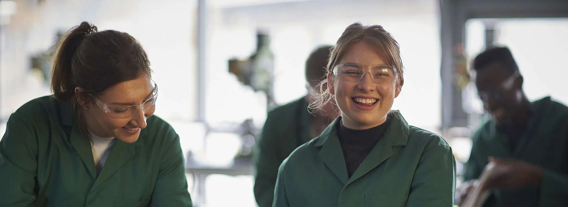 students wearing green lab coats in a workshop