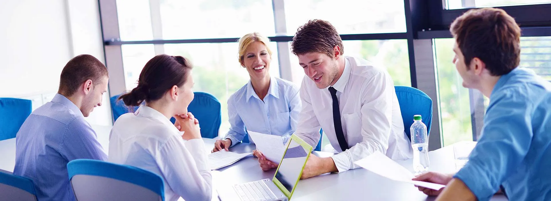 people wearing formal shirts having a meeting around a table