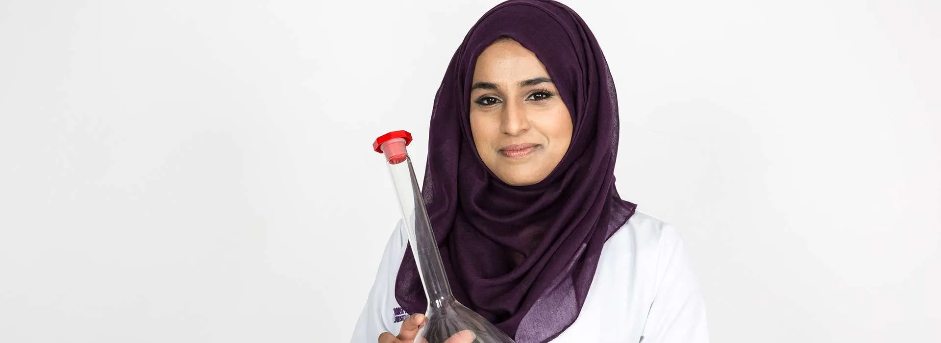 woman wearing headscarf holding large beaker