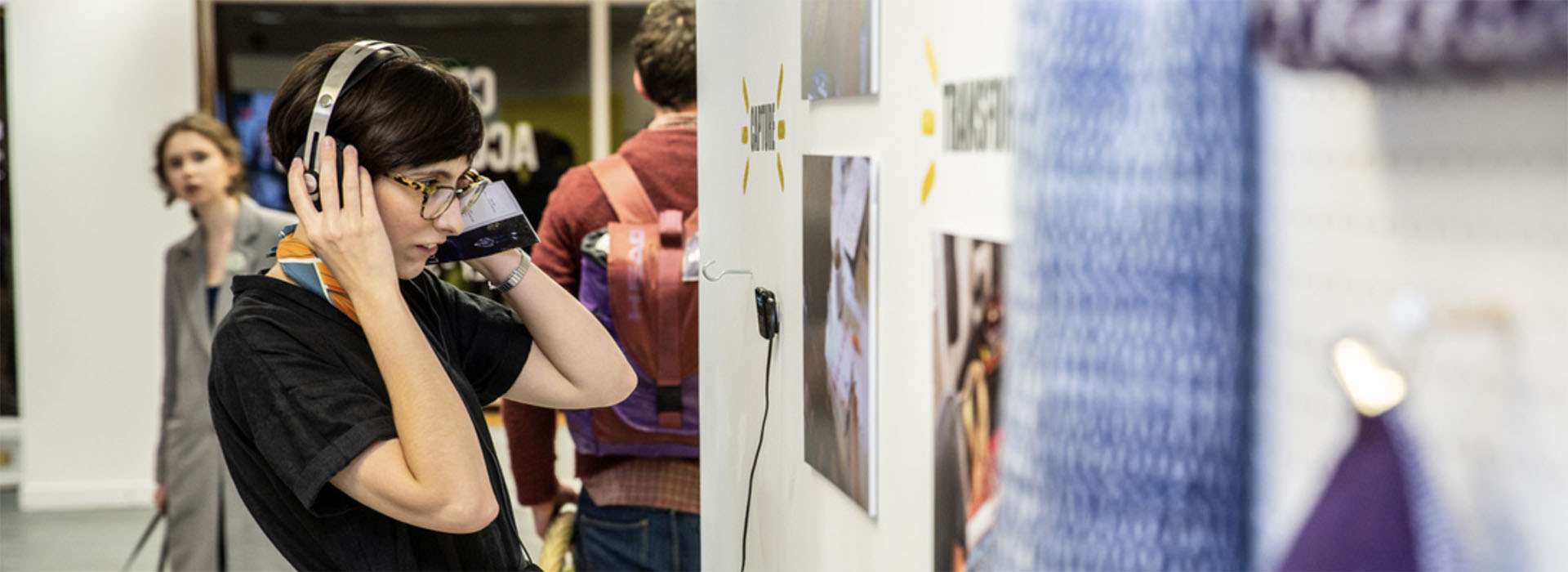 person interacting with an art display with headphones