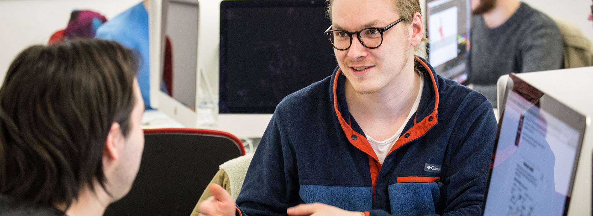 students chatting next to computers