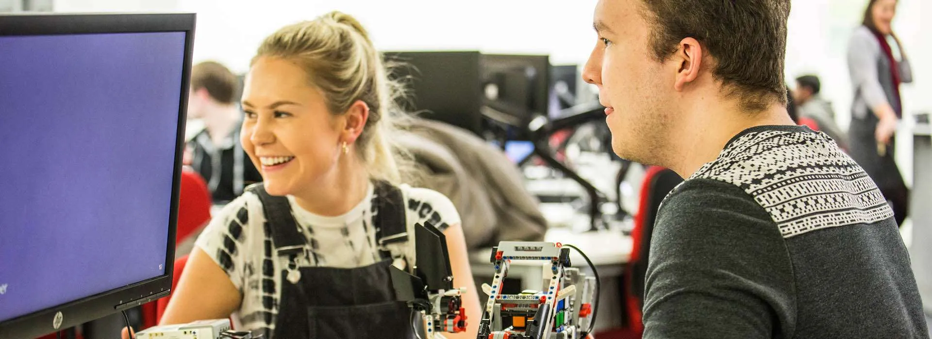 students smiling working on robotics project