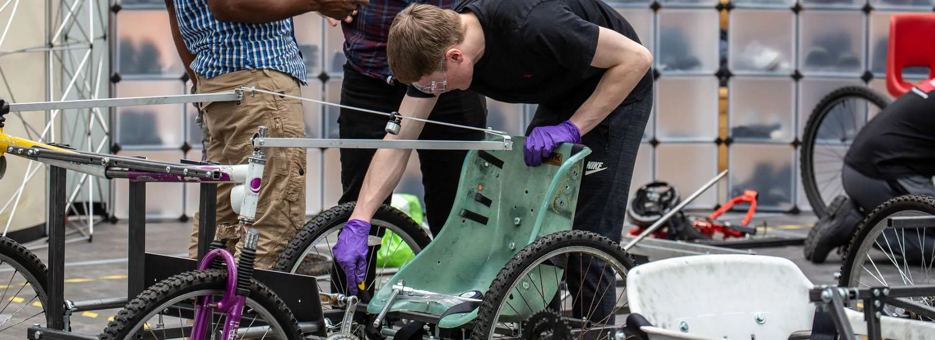 students working on vehicle with bicycle wheels