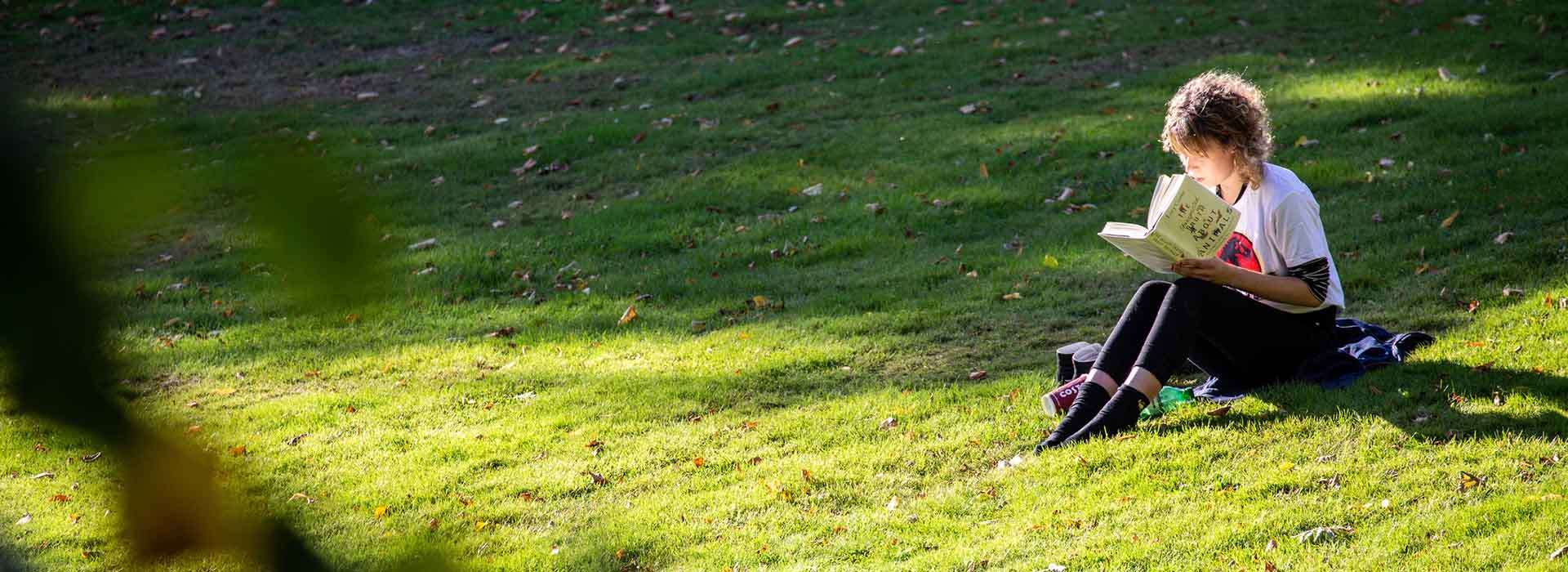 Girl studying while sat on the grass