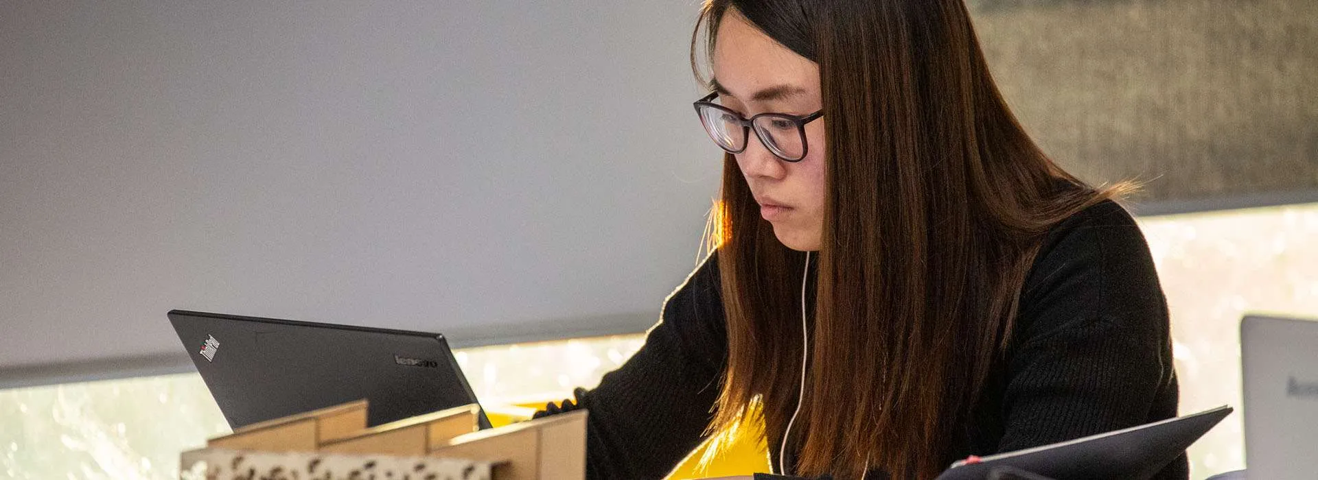 student looking at laptop next to an architectural model
