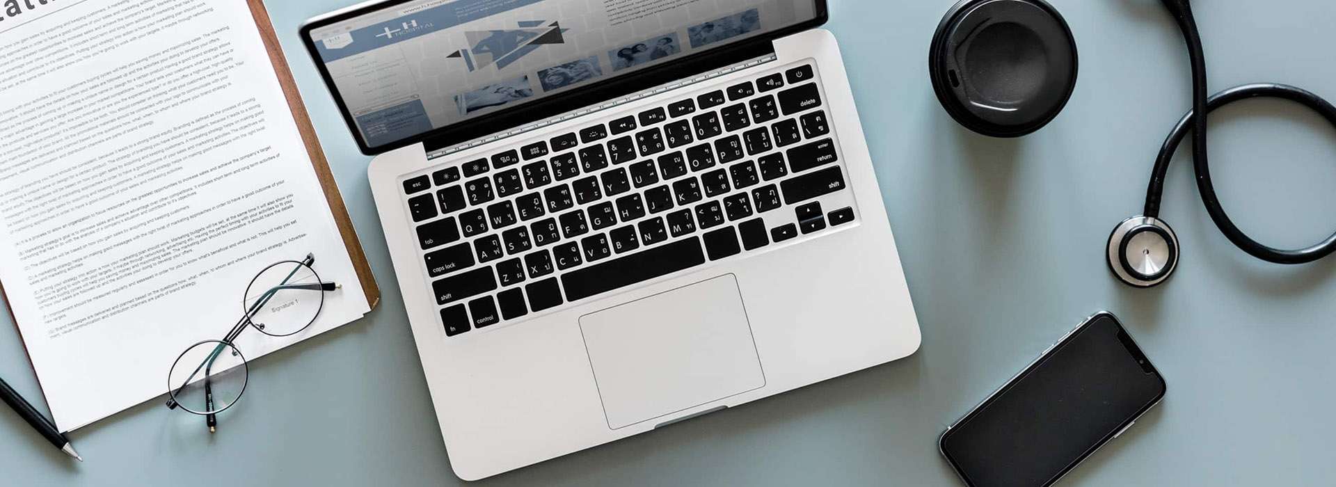 desk with laptop, documents and stethoscope