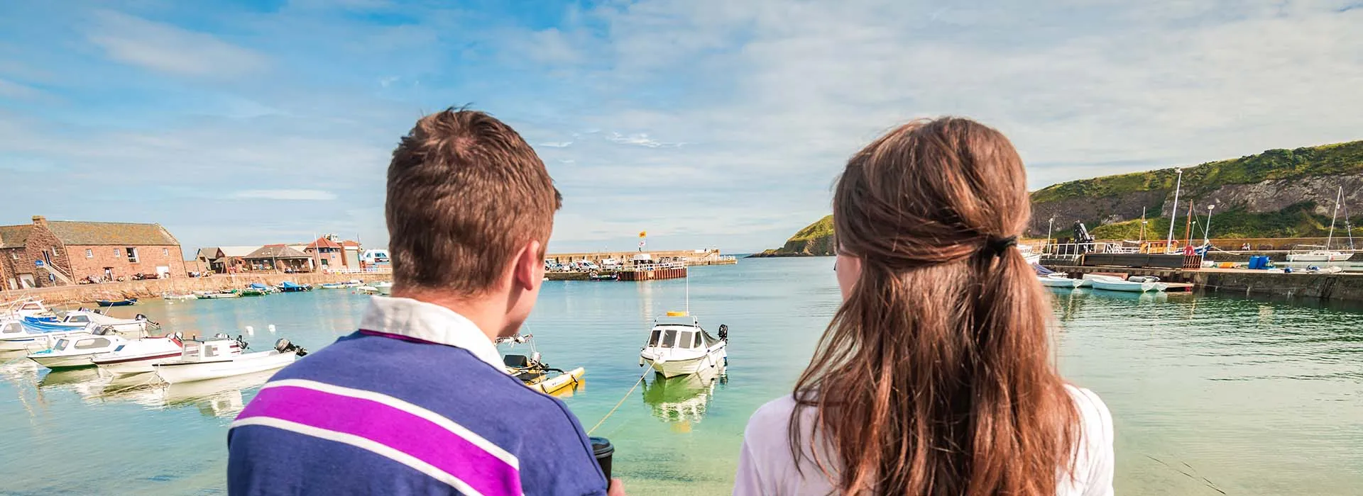 Two people sat at Stonehaven harbour looking at water and boats