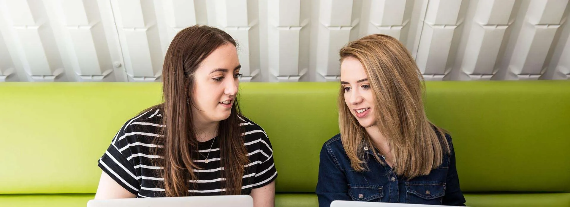 two students chatting with their laptops in front of them