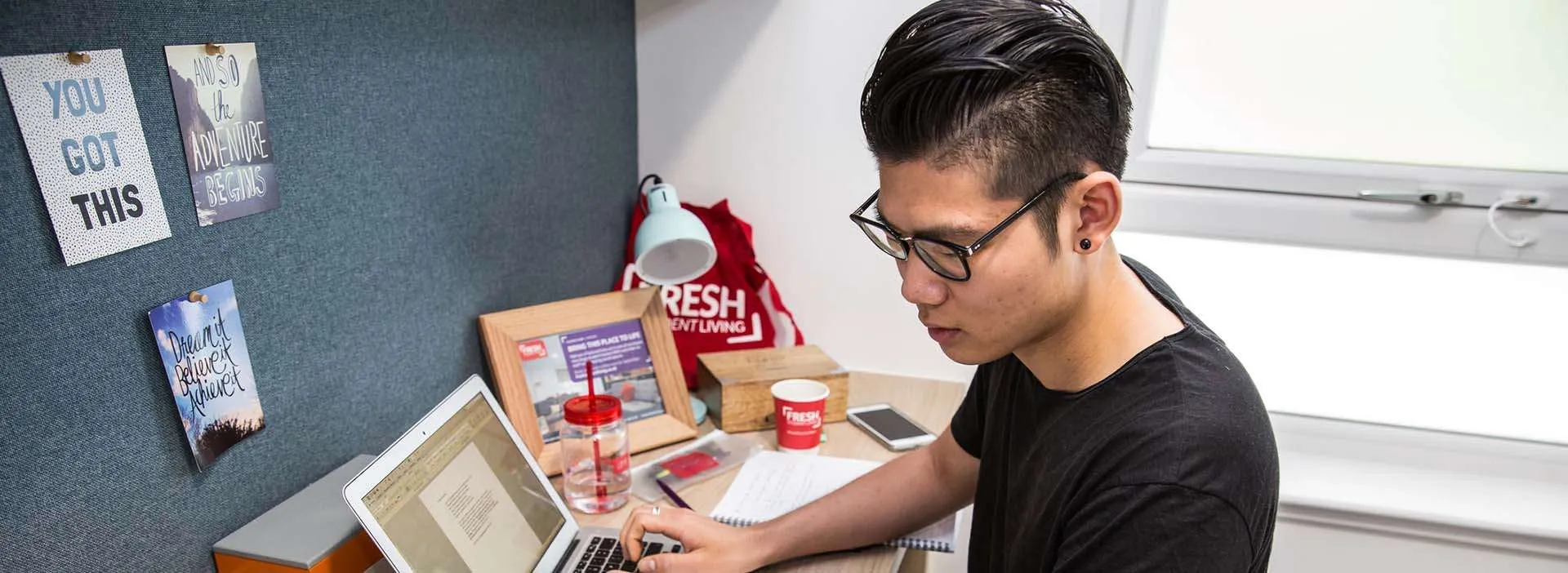 student working at his desk with a book and laptop