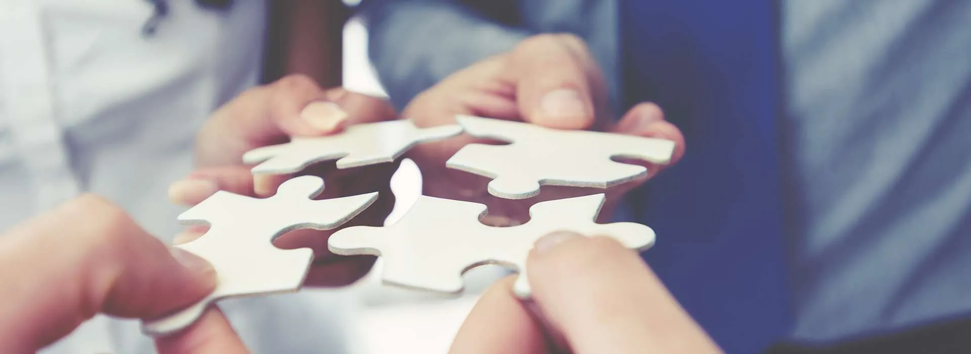 people placing jigsaw puzzle pieces together