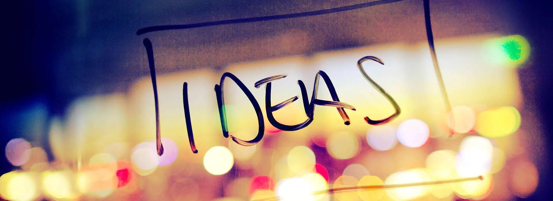 ideas written on glass in front of blurry lights