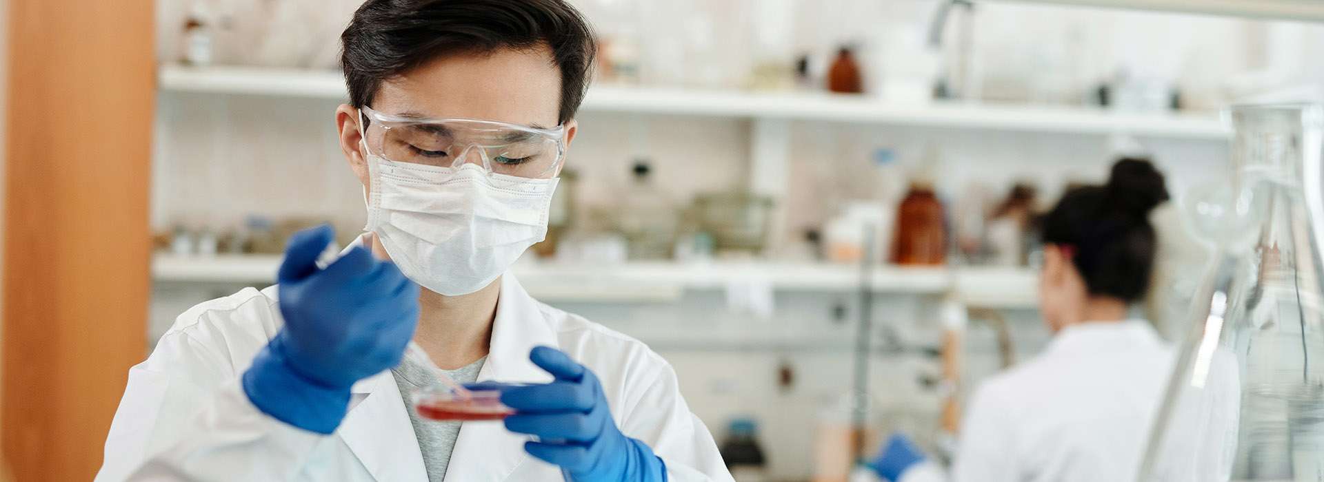 person wearing a mask in a lab using equiptment