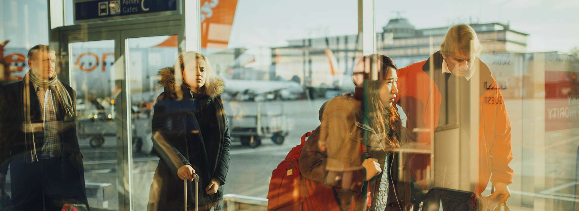 people in reflected in an airport window with planes in the background