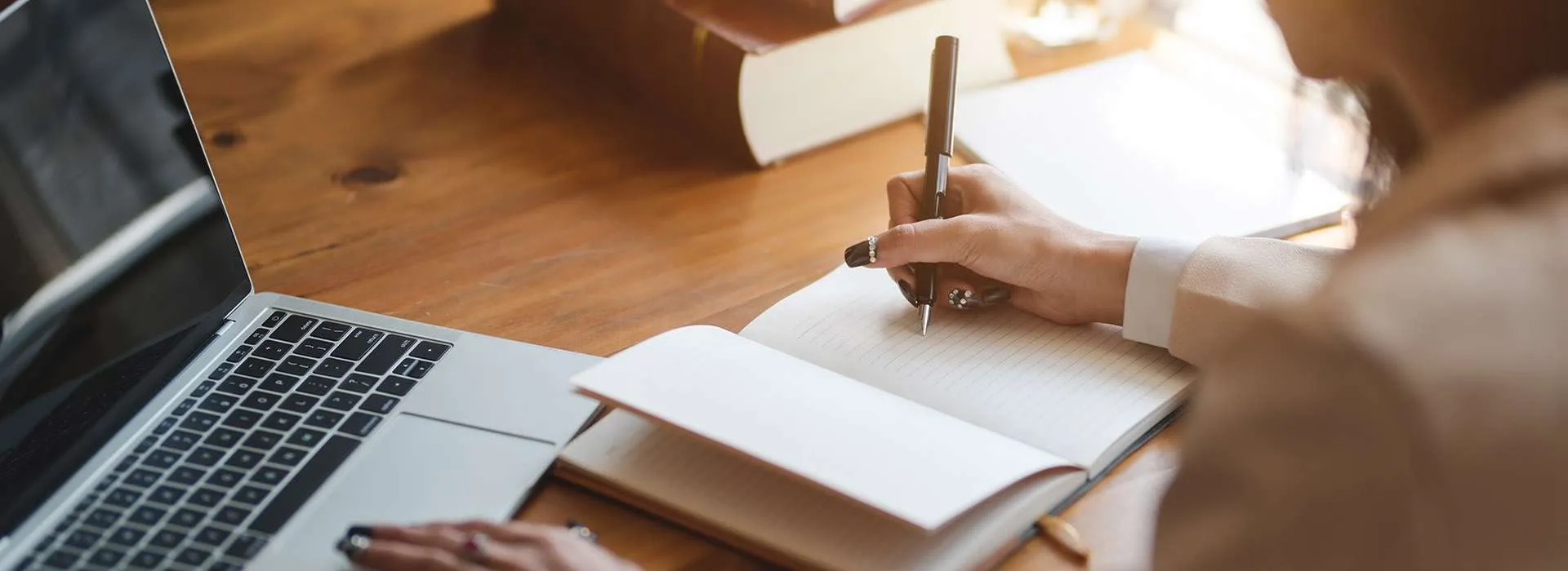 person writing in notebook on desk