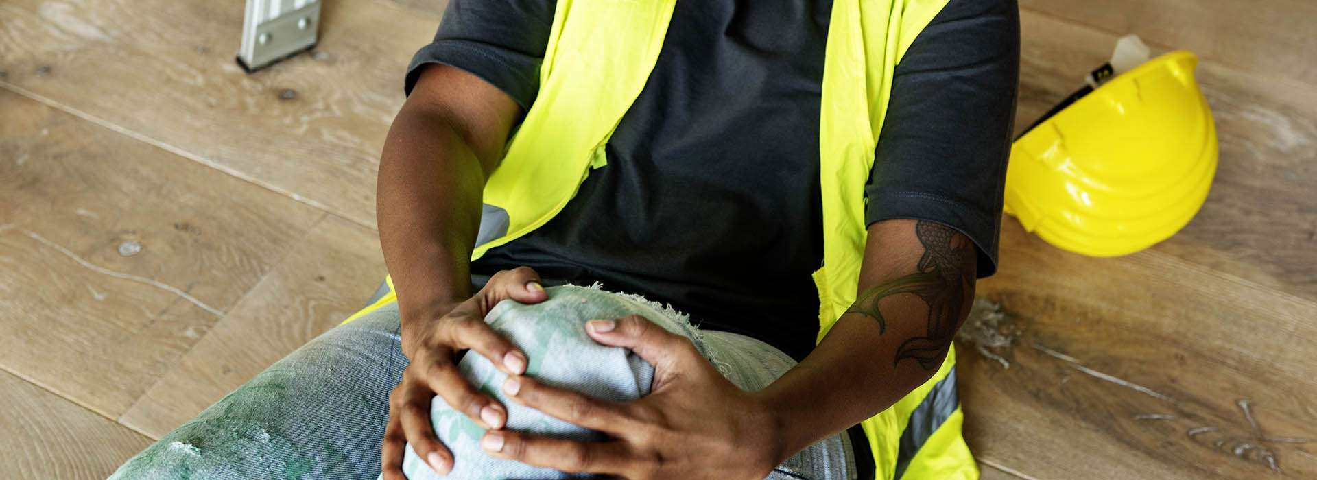 Person in high-vis holding their knee in pain