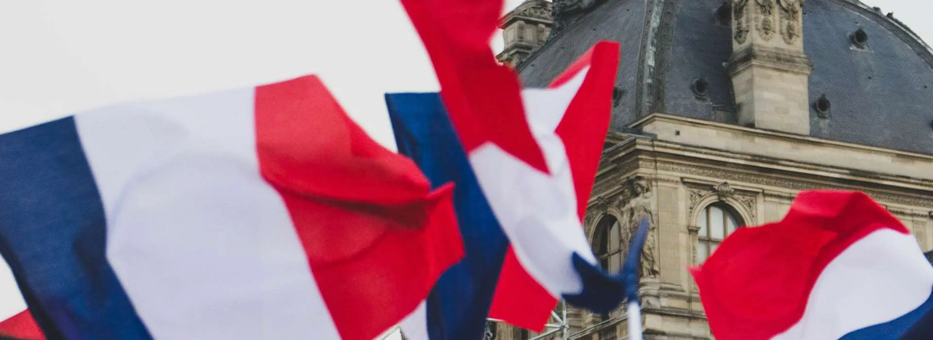 french flag flying in front of old building