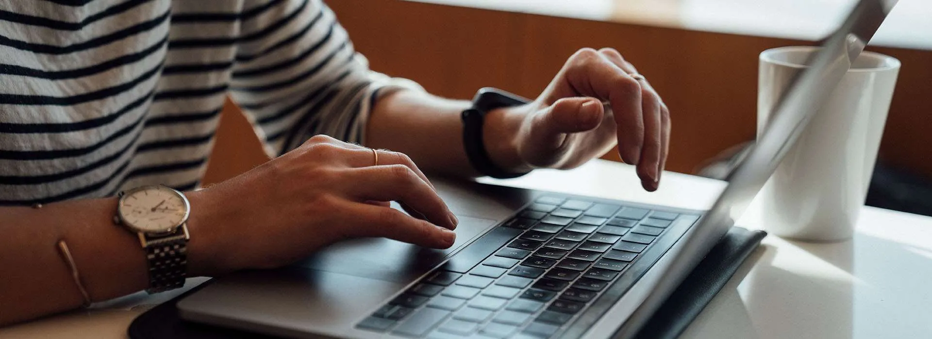 person in a striped top types on a laptop