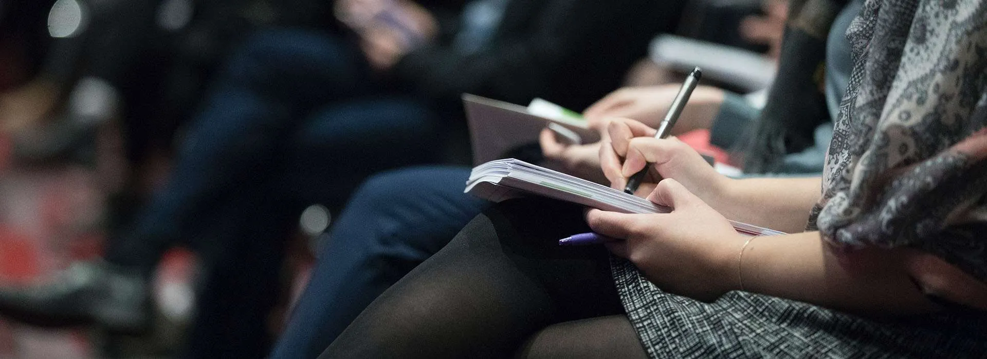 person taking notes in an audience