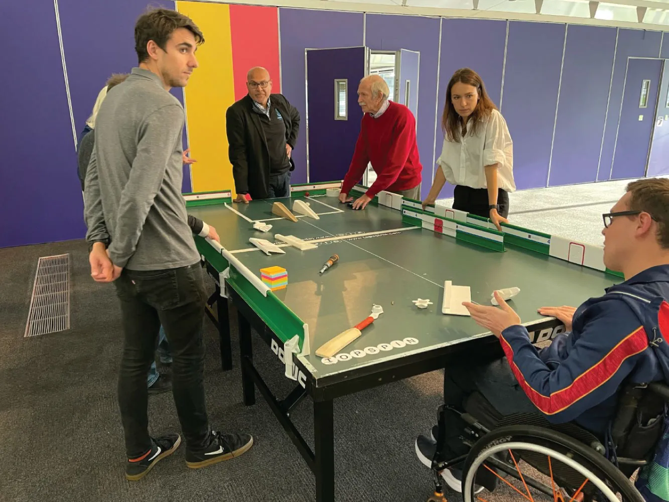 Group of people play table cricket
