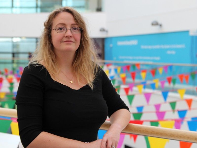 Dr Jo-Anne Tait posing in front of colourful flags at RGU