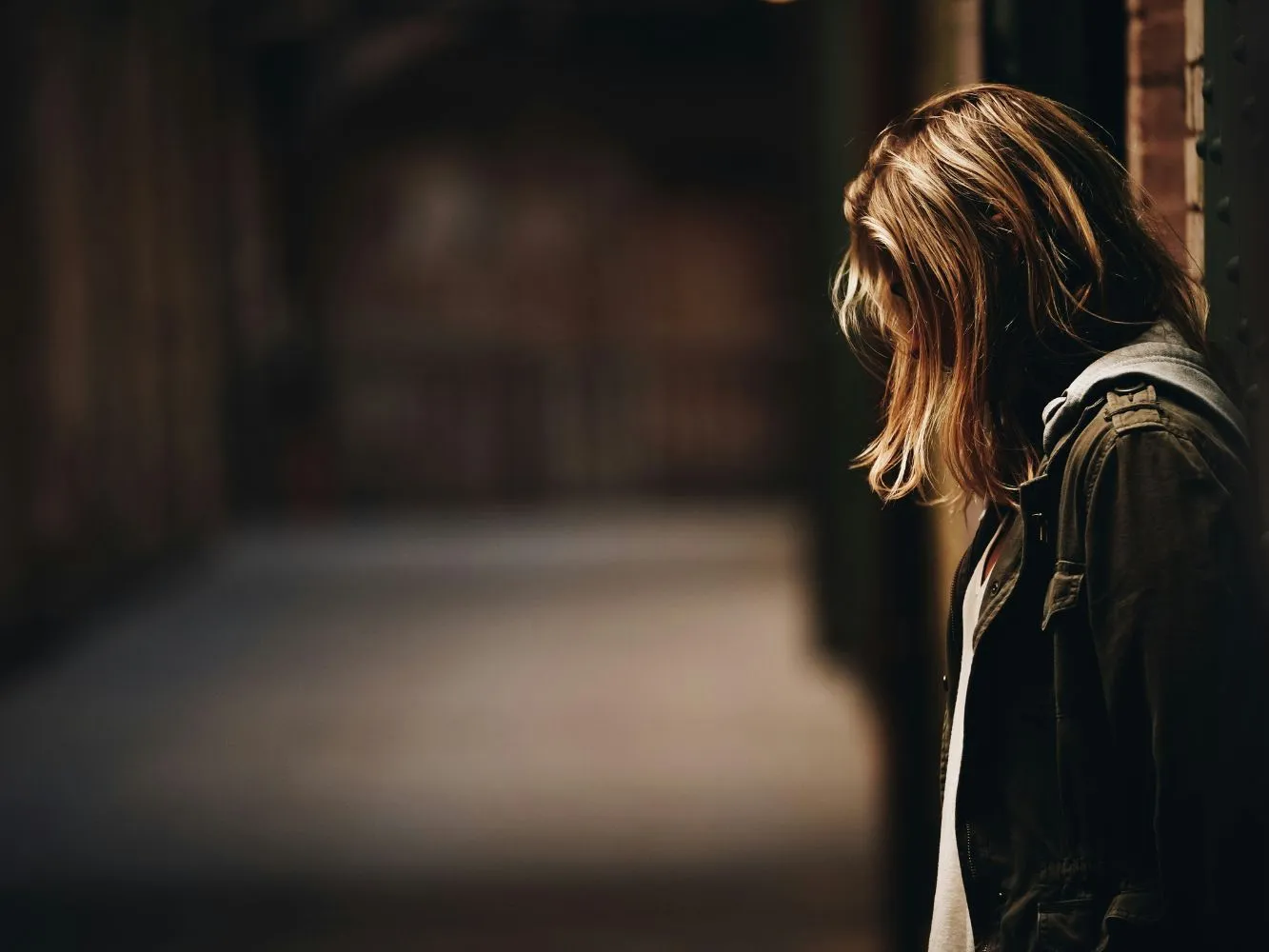 Image shows girl with depression, bowing her in head against a ball - image credit Eric Ward, Unsplash