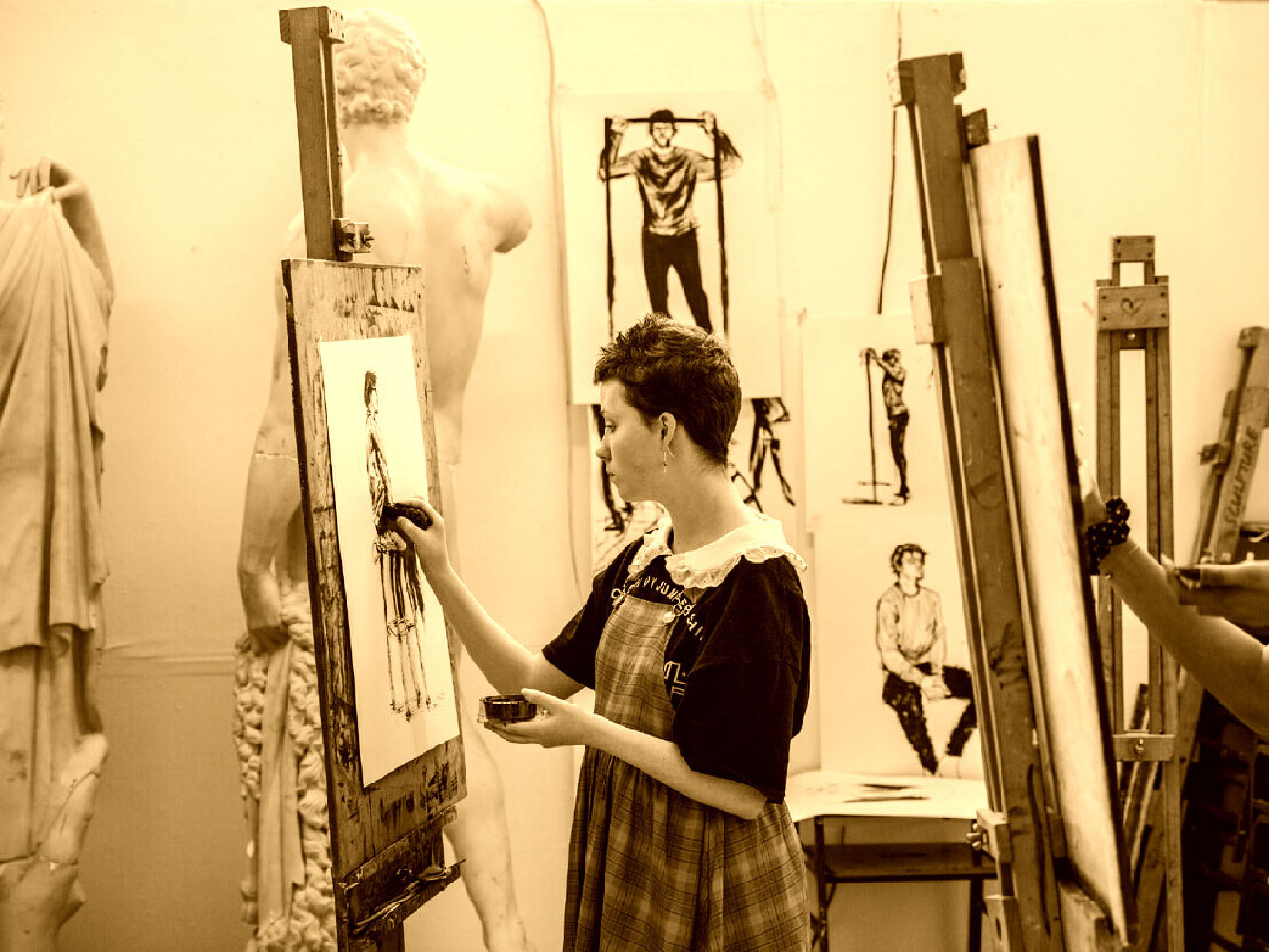 An artist paints with various artwork around them