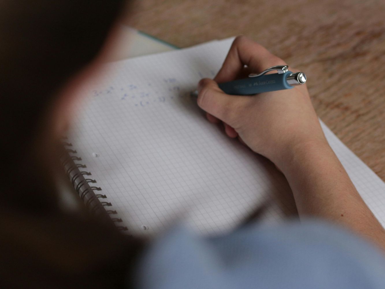 A person writing on a notepad, taken from over the shoulder