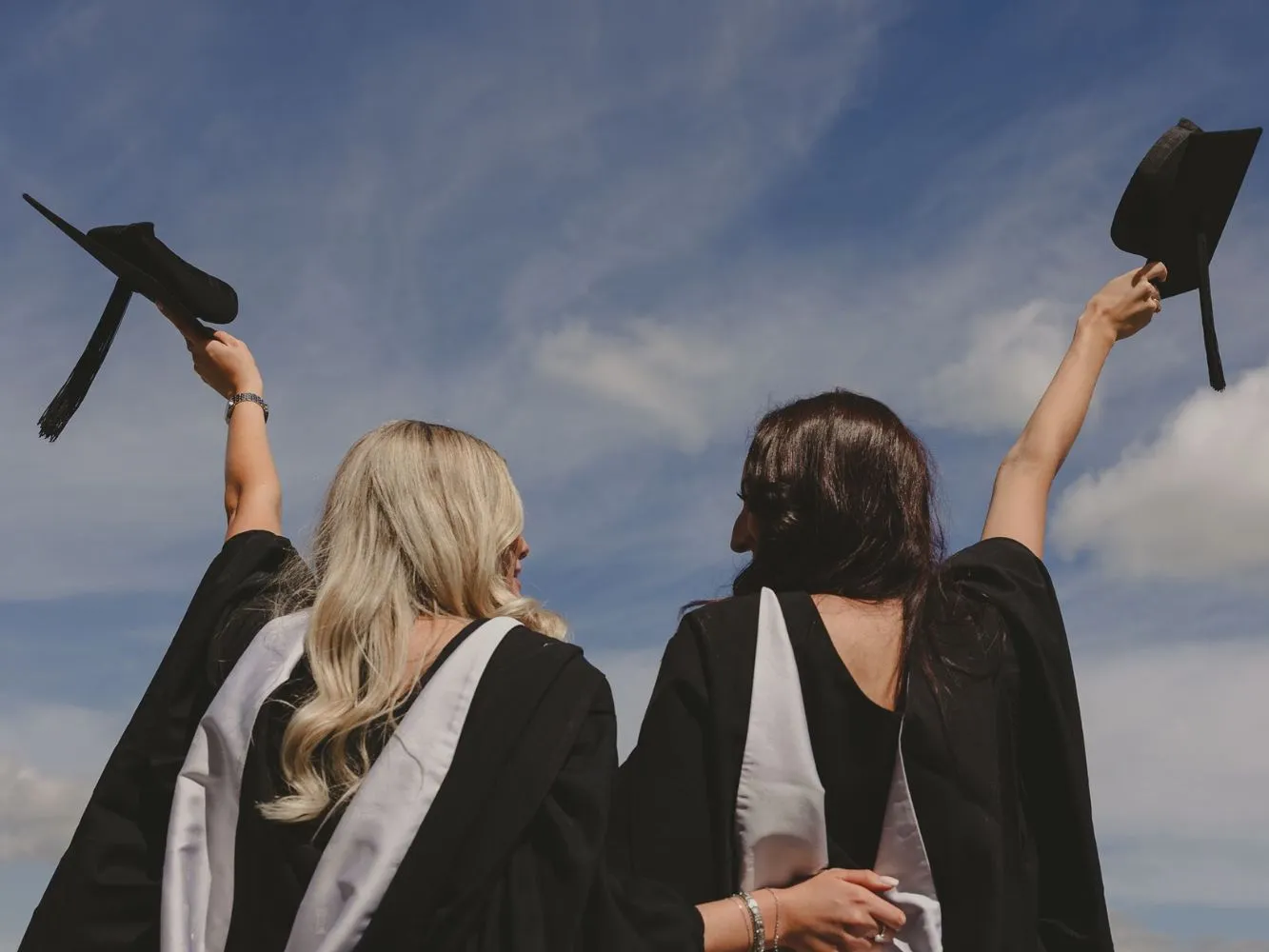Two RGU students doffing their hats at graduation