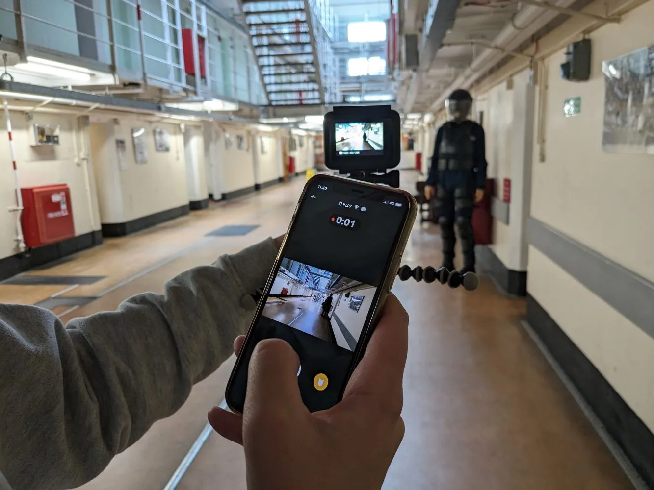A person holding a mobile phone in a former prison building