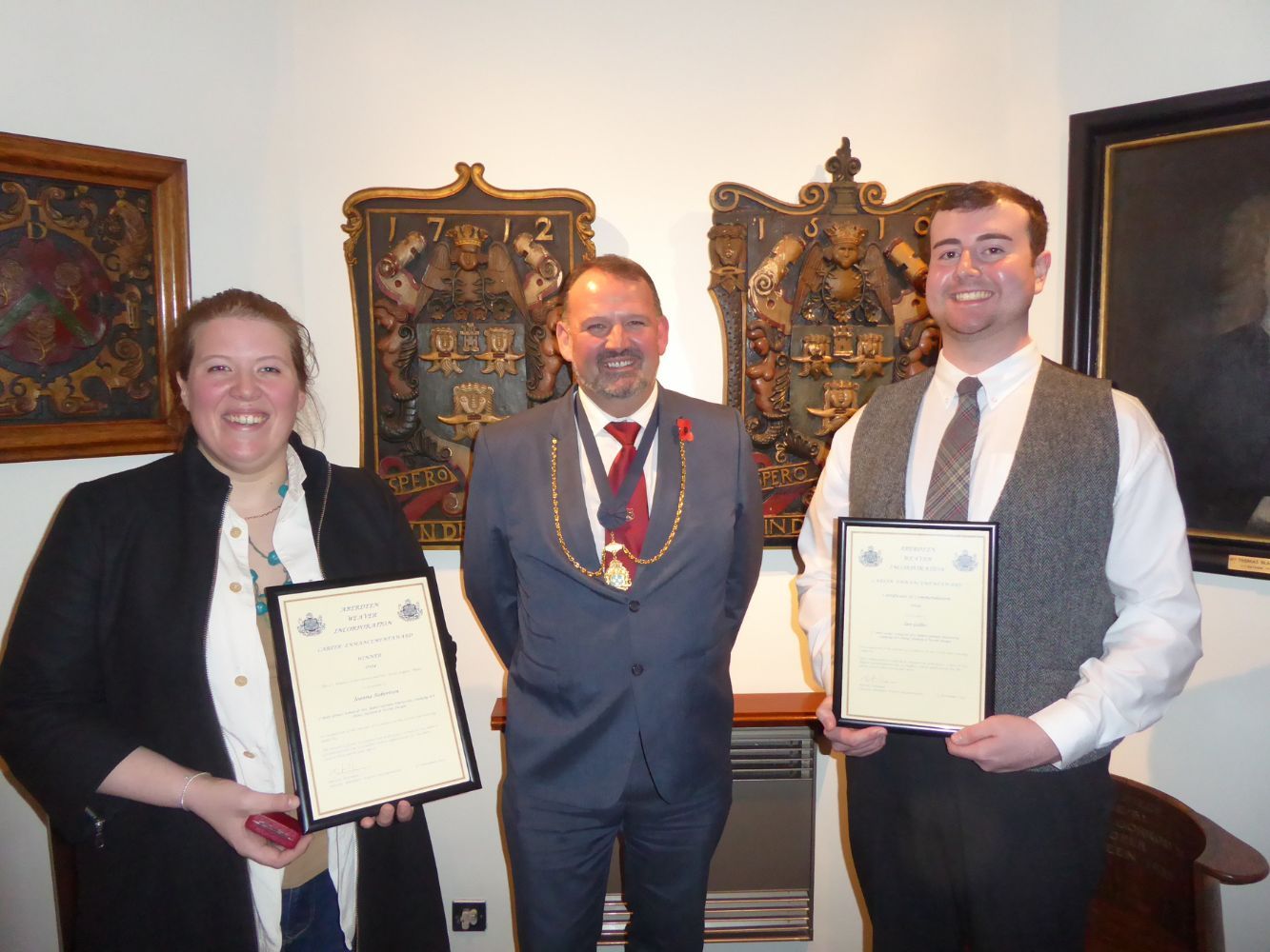 Image shows Joanna Robertson (Winner) and Iain Gillies (Runner up) both holding their Award Certificates and Joanna the J Gray Kilgour Medal with Deacon Martin Wiseman, Aberdeen Weaver's Incorporation Awards.