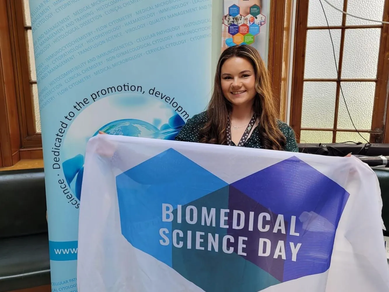 Phillippa Hulme holding a Biomedical Science Day flag