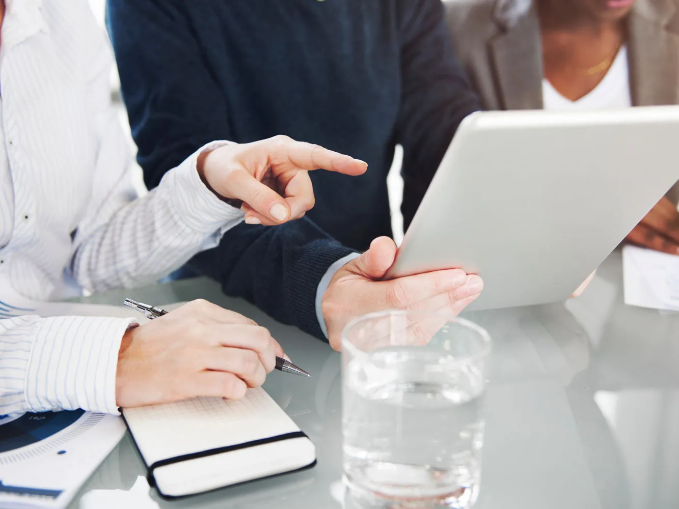 people chatting and pointing at a tablet