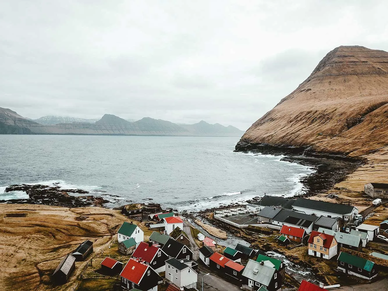 small village on the shore by dramatic hilly landscape