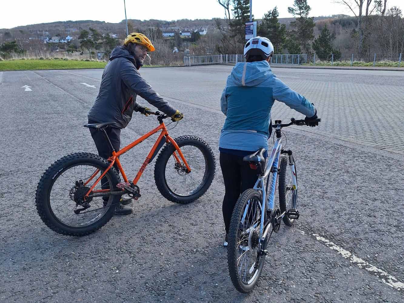 two people holding bikes by the handles and chatting