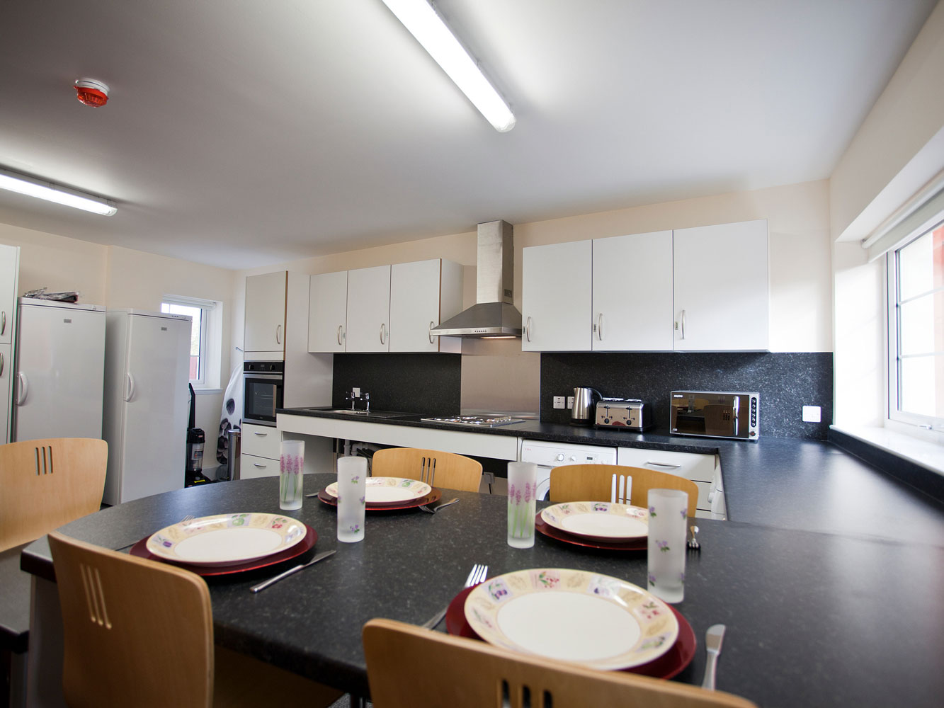 fitted kitchen area with dining space, fridge freezers and appliances