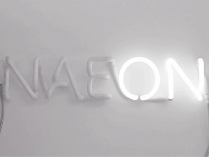 Neon light on white wall that reads 'NAEON'