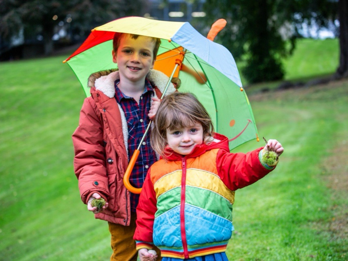 Helen Castle's two children playing outdoors, one holds an umbrella