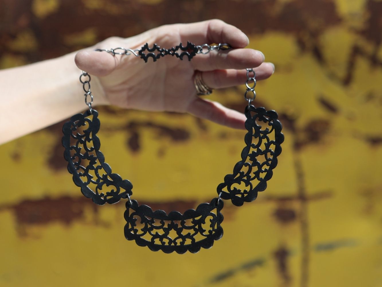 Intricately designed handmade necklace held up by hand