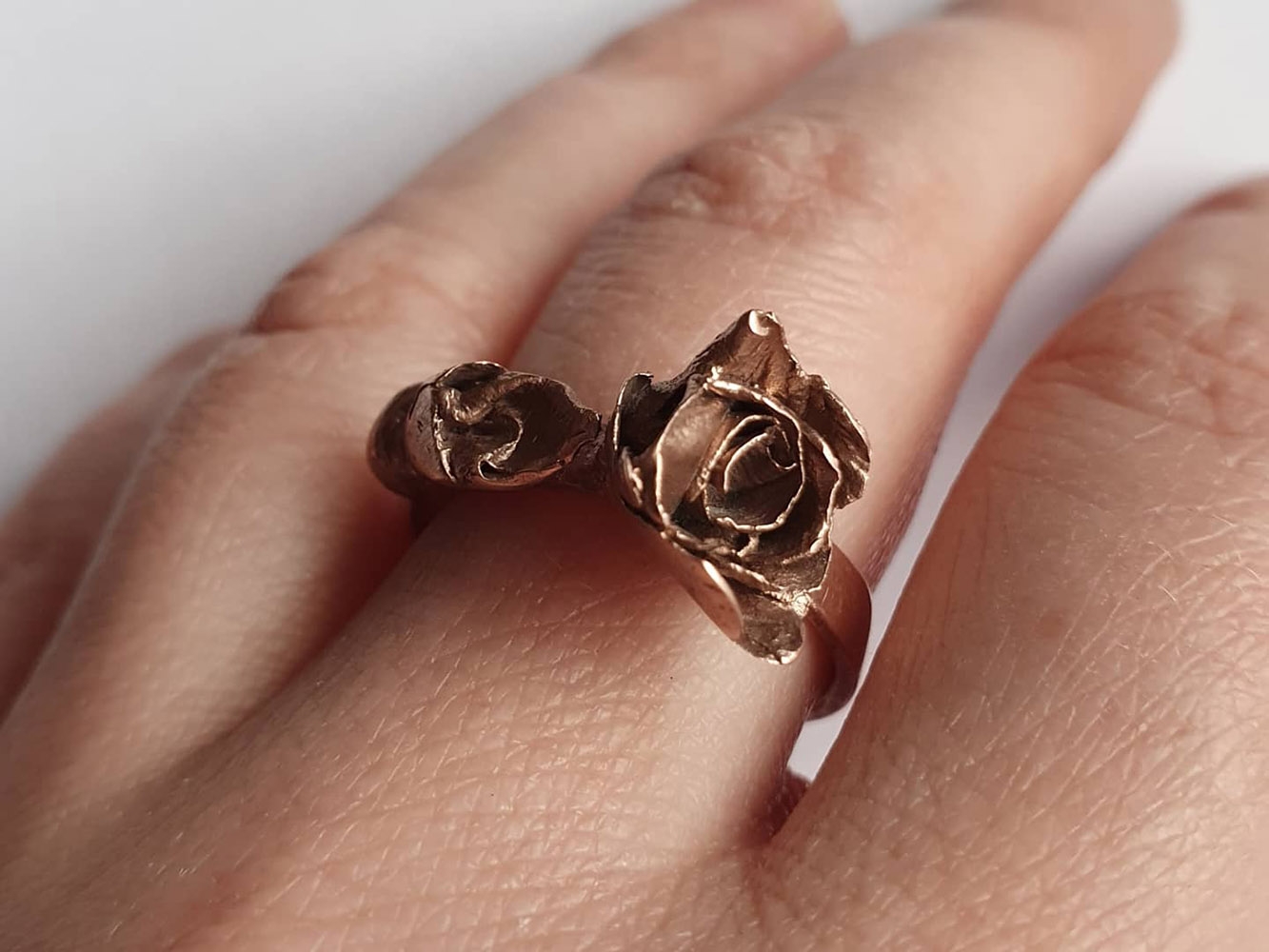 Copper rose-shaped ring worn on a hand