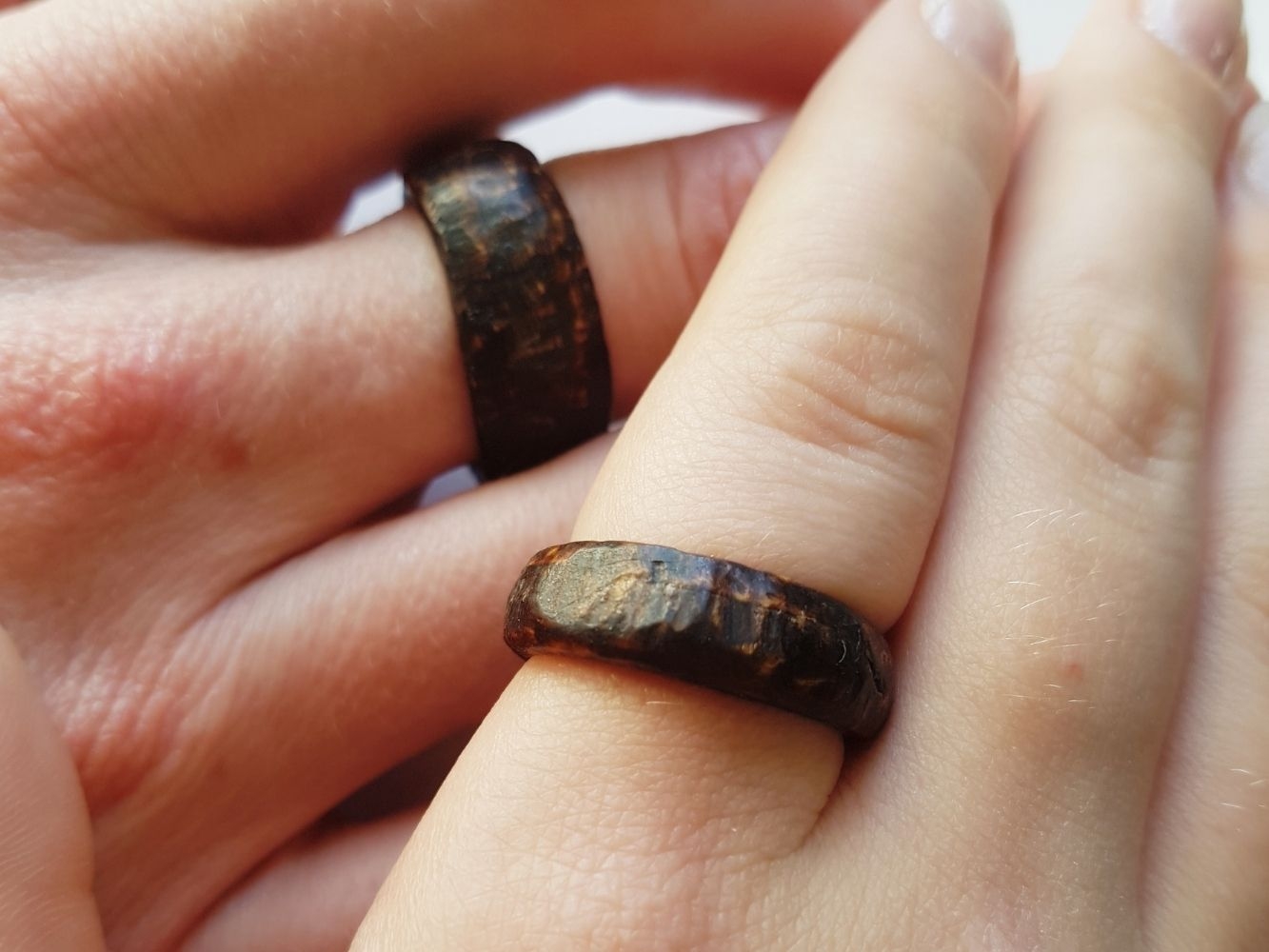 Two rings made with dark wood worn fingers